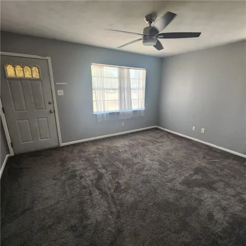 an empty room with windows and fan