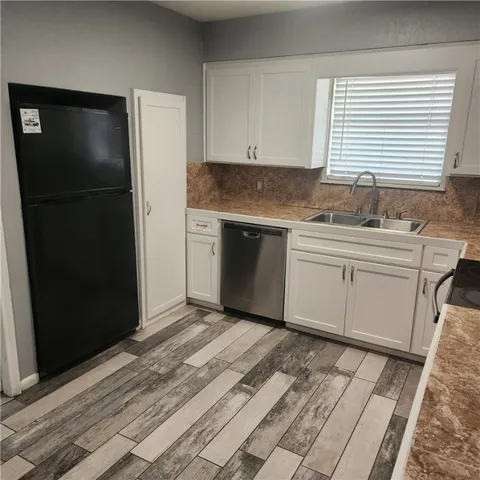 a kitchen with granite countertop white cabinets and refrigerator