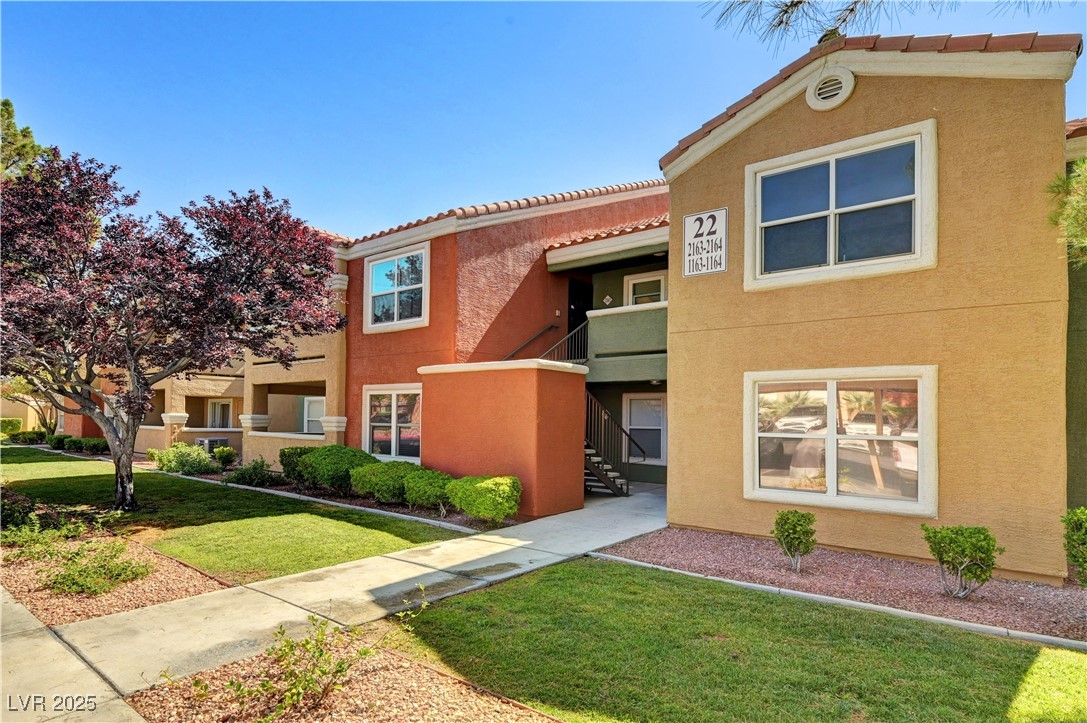 Mediterranean / spanish house featuring a front yard, stucco siding, a tile roof, and a balcony