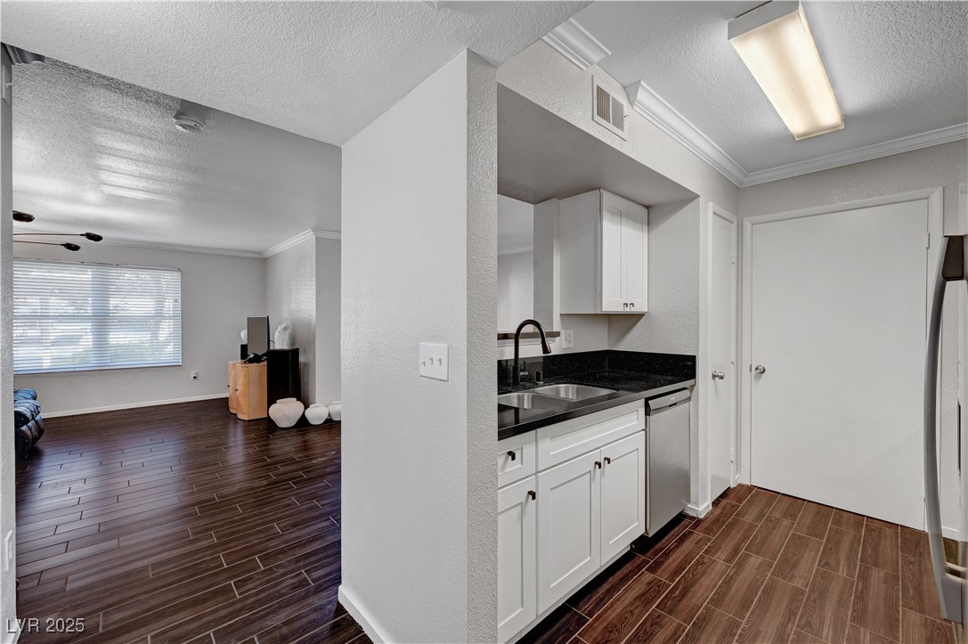 8101 West Flamingo Road, Unit 1163 Las Vegas, NV 89147 - Photo 45 of 45 Kitchen featuring a textured ceiling, wood finish floors, crown molding, white cabinets, and open floor plan