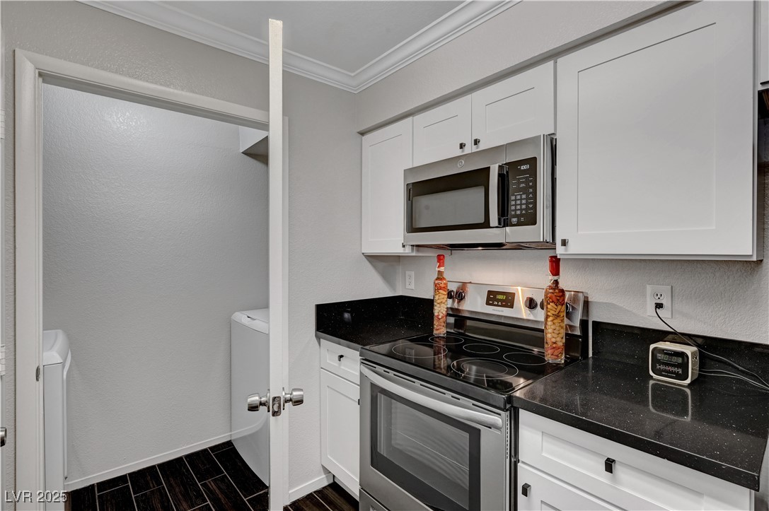 8101 West Flamingo Road, Unit 1163 Las Vegas, NV 89147 - Photo 12 of 45 Kitchen featuring stainless steel appliances, wood finish floors, a textured wall, ornamental molding, and white cabinets