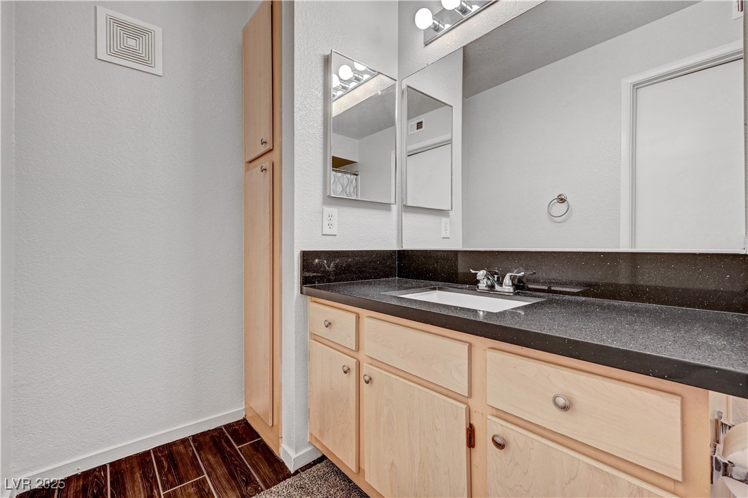 8101 West Flamingo Road, Unit 1163 Las Vegas, NV 89147 - Photo 17 of 45 Bathroom with wood finish floors, vanity, and a textured wall