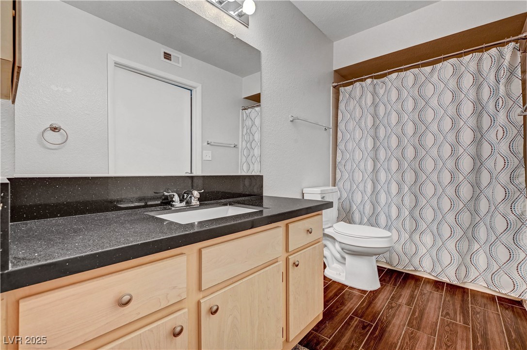 8101 West Flamingo Road, Unit 1163 Las Vegas, NV 89147 - Photo 18 of 45 Full bathroom with wood tiled floors, vanity, a textured wall, and a shower with shower curtain