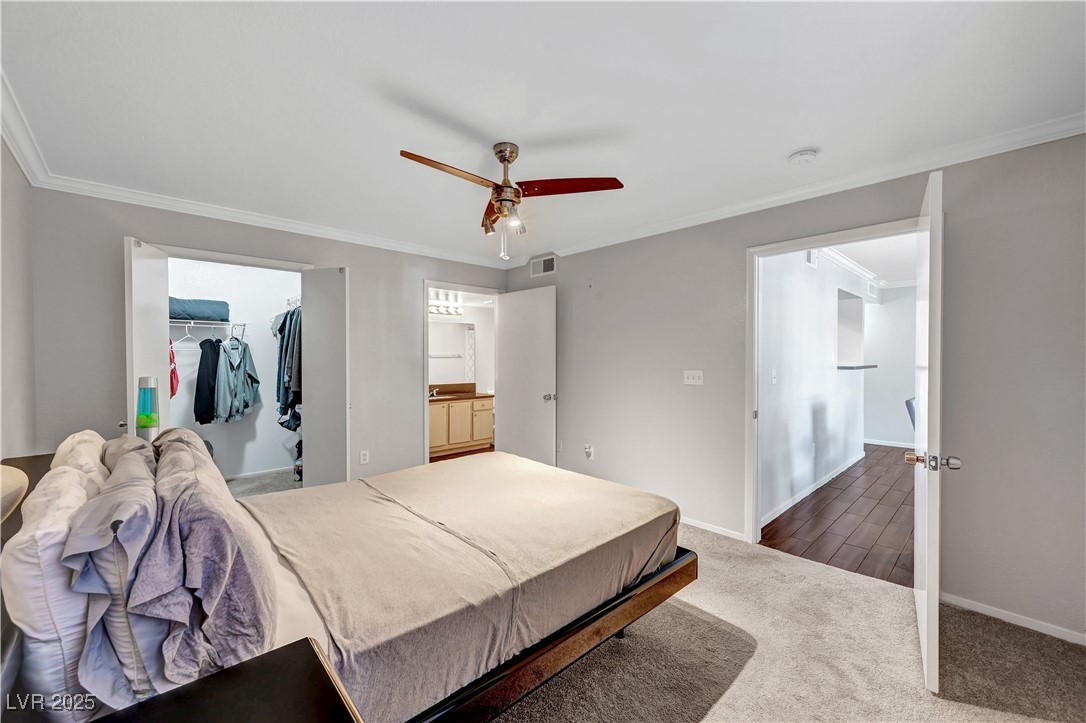 8101 West Flamingo Road, Unit 1163 Las Vegas, NV 89147 - Photo 26 of 45 Bedroom with ornamental molding, dark colored carpet, ceiling fan, and a walk in closet