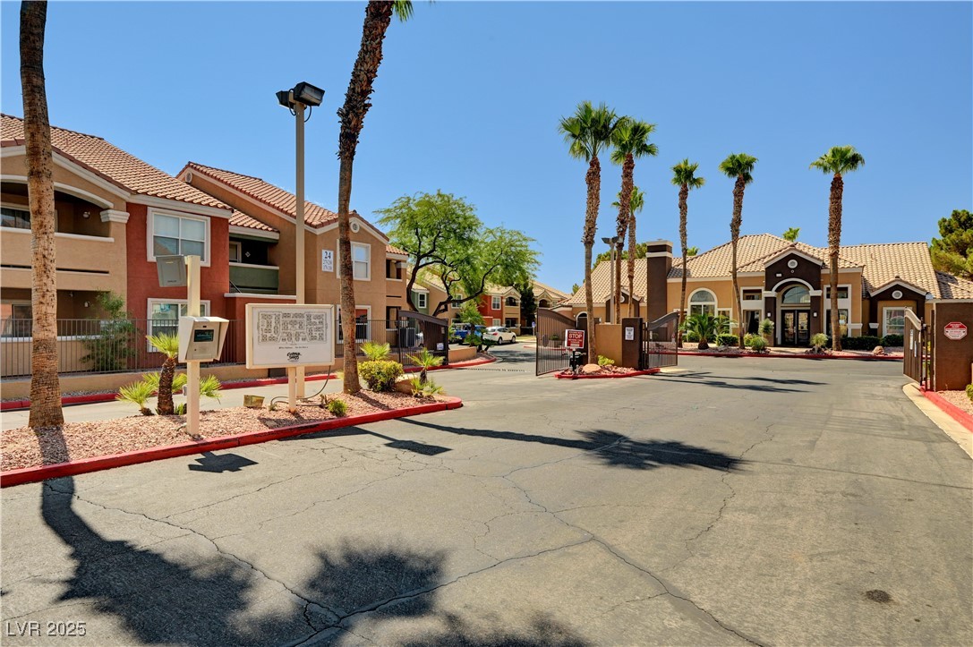 8101 West Flamingo Road, Unit 1163 Las Vegas, NV 89147 - Photo 31 of 45 View of asphalt road with a gated entry, curbs, a residential view, and street lights