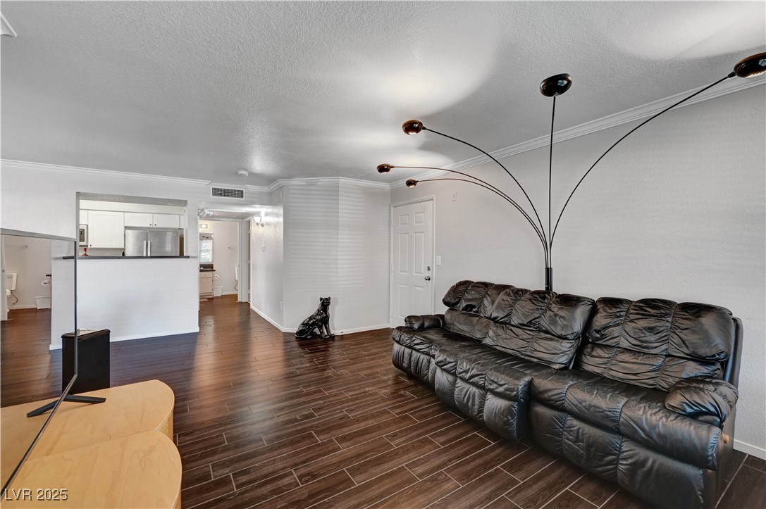 8101 West Flamingo Road, Unit 1163 Las Vegas, NV 89147 - Photo 5 of 45 Living room featuring crown molding, wood tiled floors, and a textured ceiling