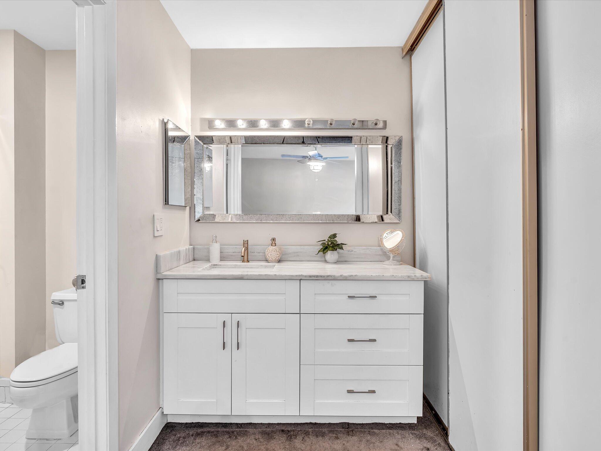 4441 Northwest 22nd Road, Unit 414 Coconut Creek, FL 33066 - Photo 29 of 60 a bathroom with a sink a toilet and a mirror