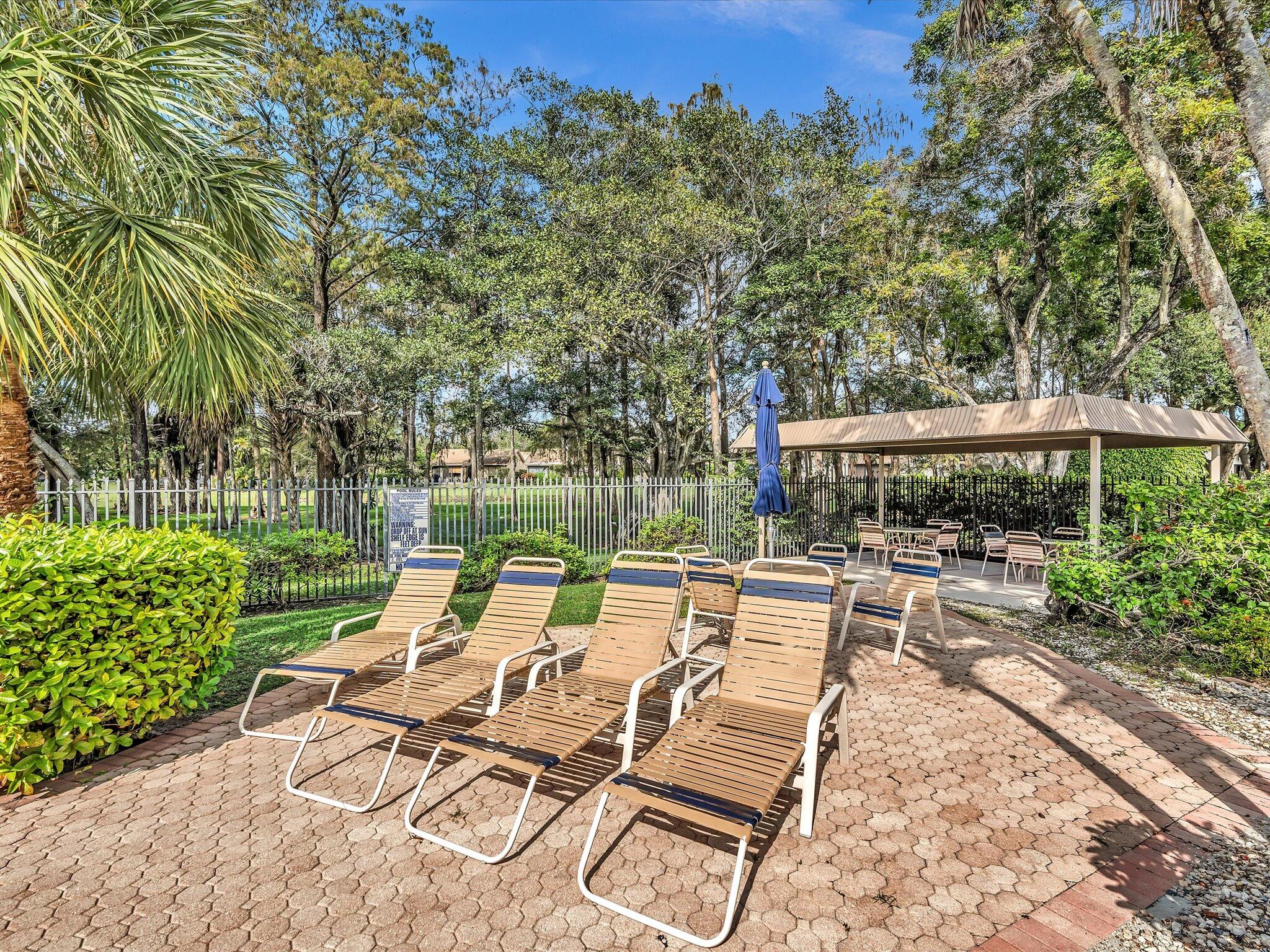 4441 Northwest 22nd Road, Unit 414 Coconut Creek, FL 33066 - Photo 47 of 60 a view of a patio with a dining table and chairs with wooden fence