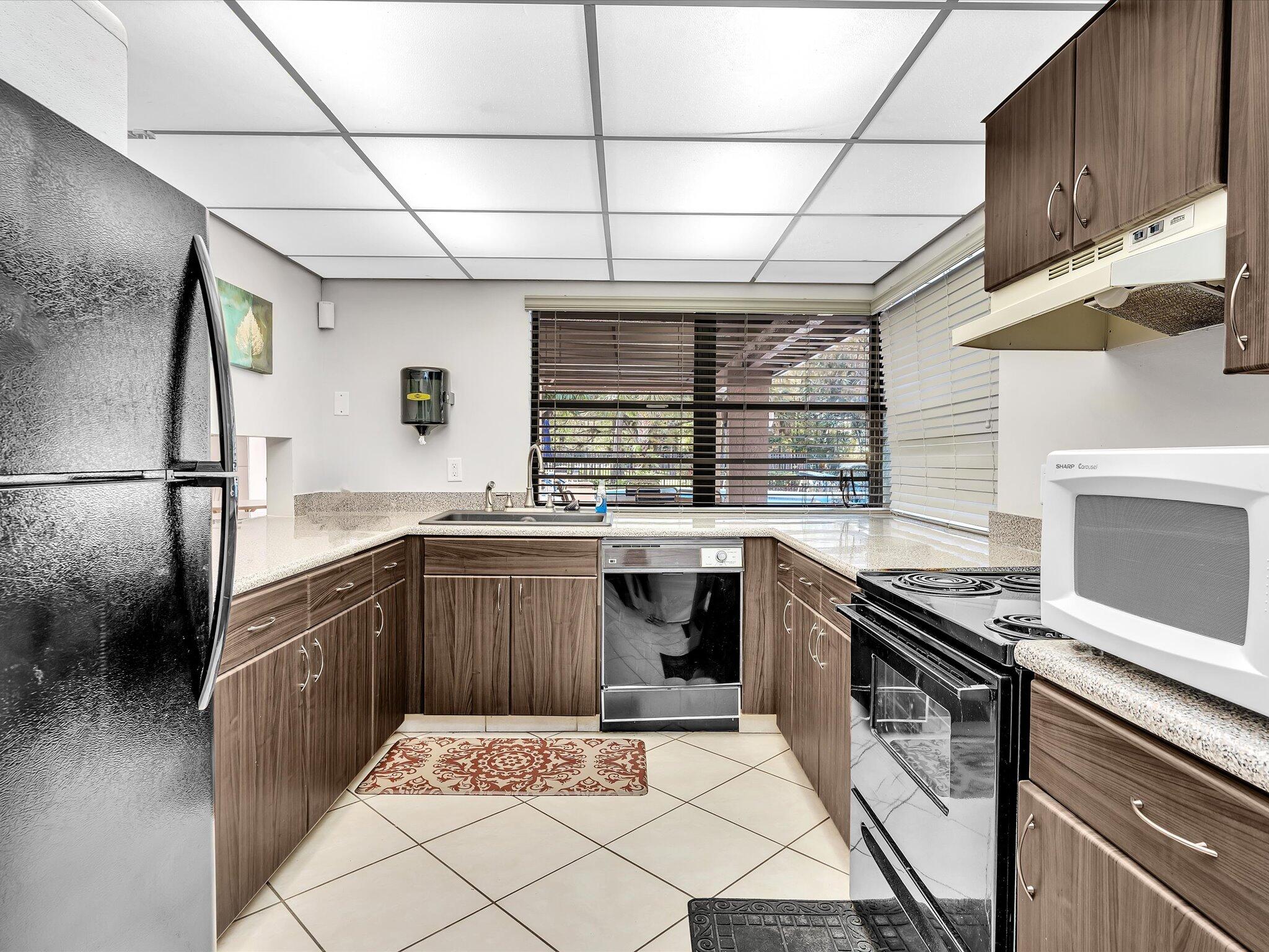 4441 Northwest 22nd Road, Unit 414 Coconut Creek, FL 33066 - Photo 51 of 60 a kitchen with stainless steel appliances granite countertop a sink and wooden cabinets