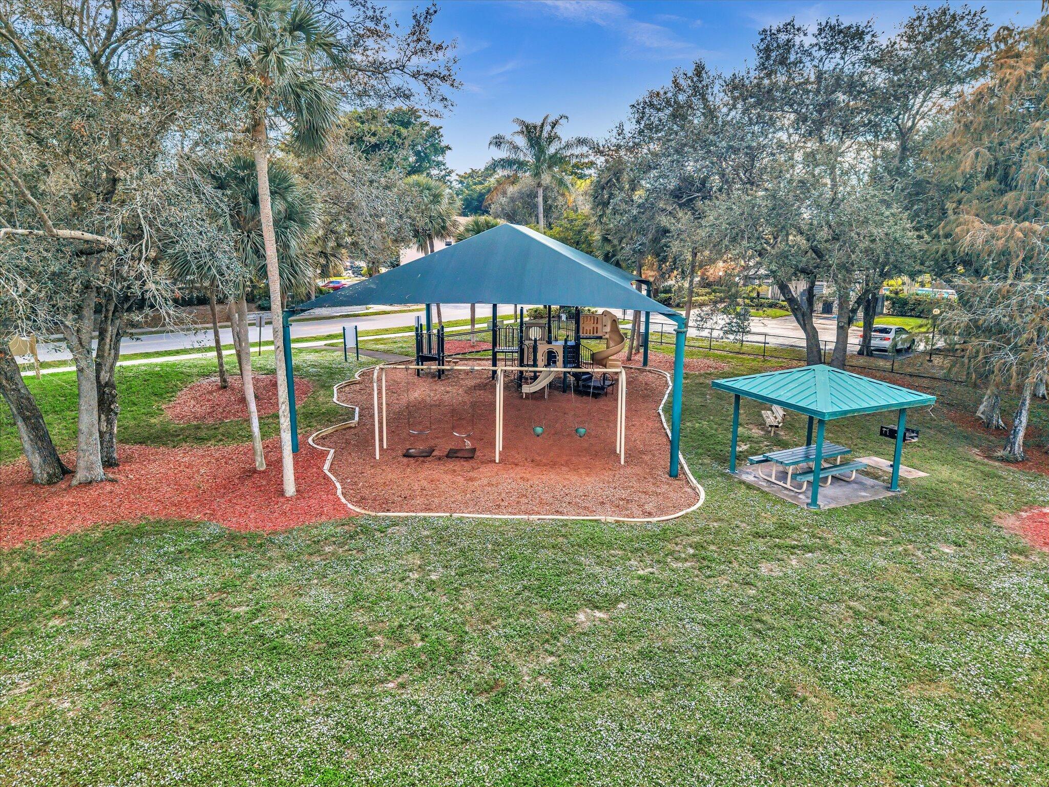 4441 Northwest 22nd Road, Unit 414 Coconut Creek, FL 33066 - Photo 52 of 60 a view of a backyard with table and chairs under an umbrella