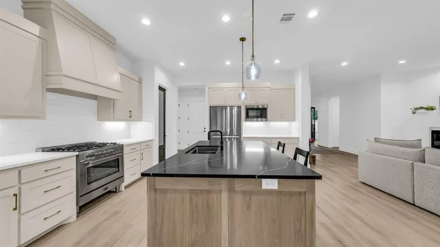 a large kitchen with stainless steel appliances granite countertop a lot of counter space and wooden floors