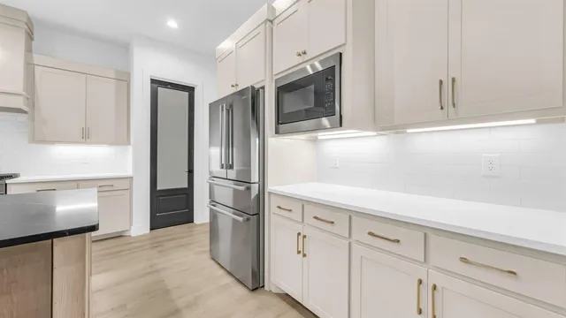 a kitchen with stainless steel appliances white cabinets and a refrigerator