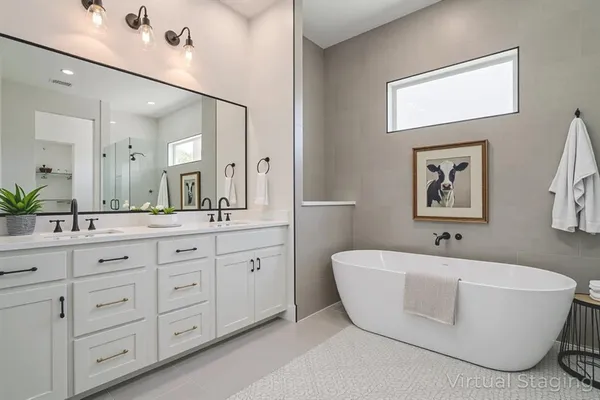 a bathroom with a bathtub a double vanity sink and mirror