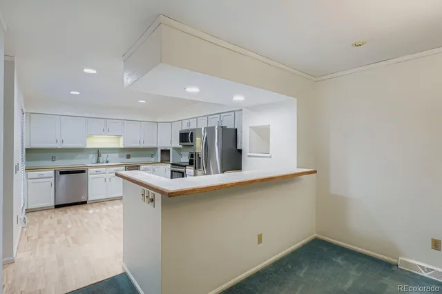 a kitchen with a sink a counter top space stainless steel appliances and cabinets