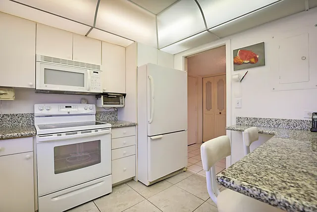 a kitchen with stainless steel appliances granite countertop a refrigerator sink stove and white cabinets