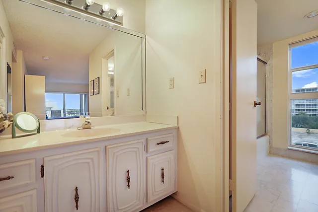 a bathroom with a granite countertop sink two mirror and shower