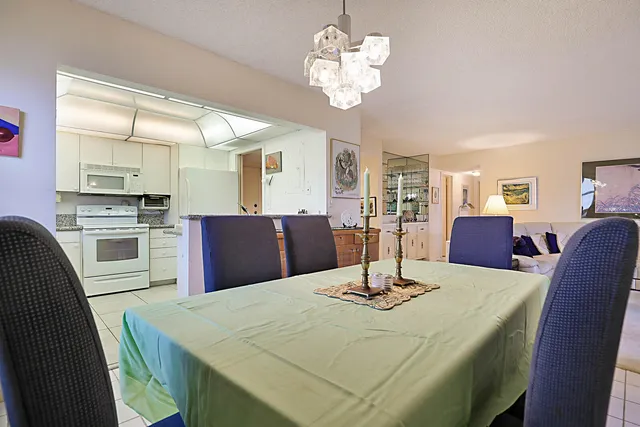 a kitchen with stainless steel appliances kitchen island granite countertop a table chairs and a refrigerator