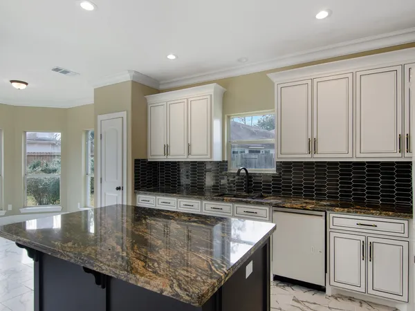 a kitchen with granite countertop a sink a stove and cabinets