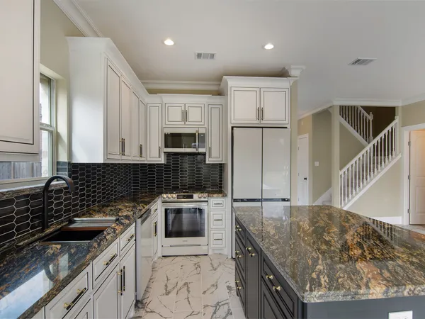 a kitchen with granite countertop a sink a stove oven and refrigerator