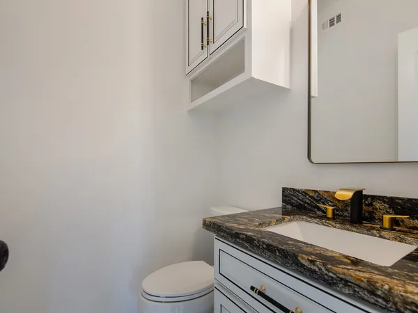 a bathroom with a granite countertop toilet and sink