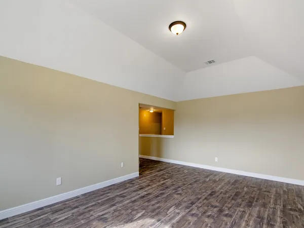a view of an empty room with wooden floor and window