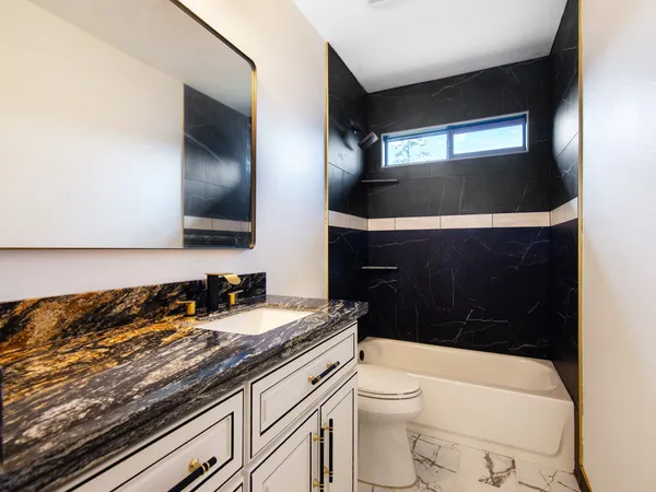 a bathroom with a granite countertop toilet sink and mirror
