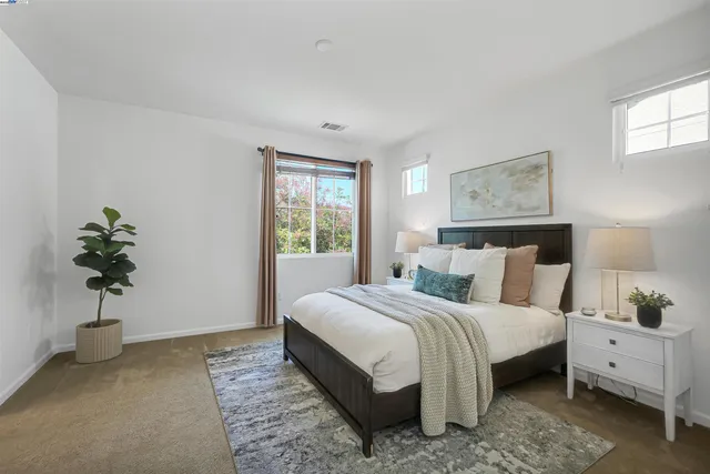 a bedroom with a bed large mirror and potted plant