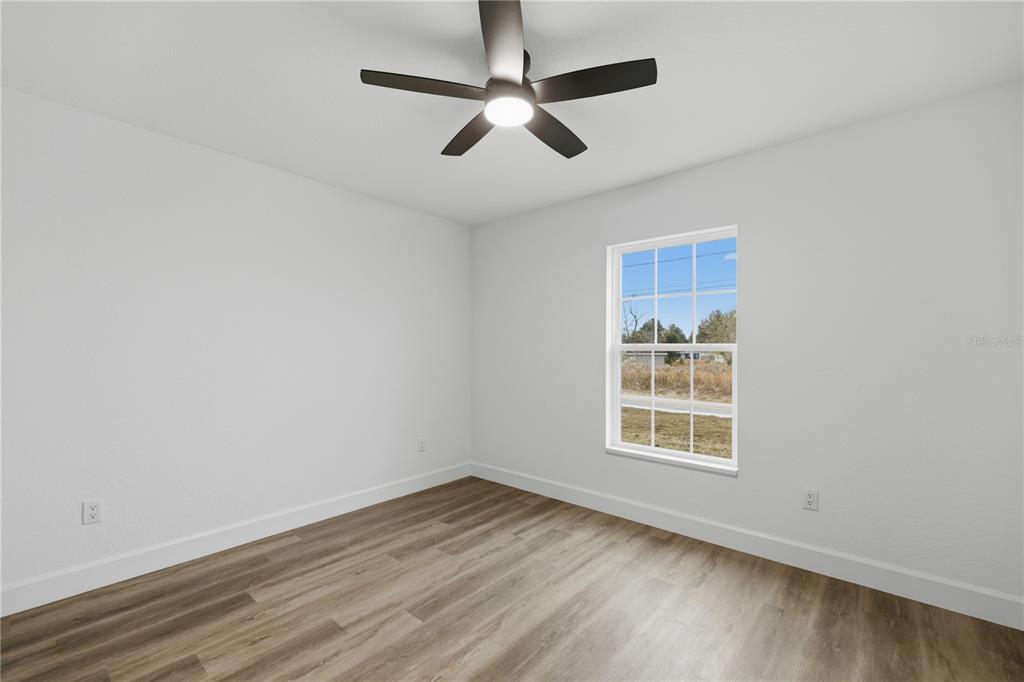 23 Juniper Loop Court Ocala, FL 34480 - Photo 17 of 25 an empty room with wooden floor ceiling fan and windows
