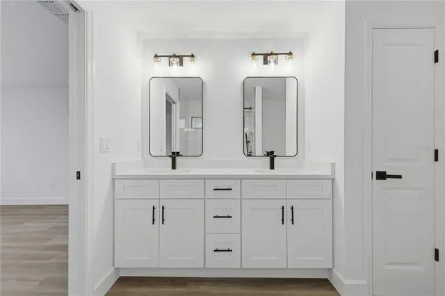 a bathroom with double vanity white cabinets and a granite counter tops