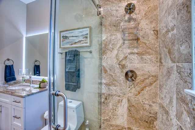 a bathroom with a granite countertop sink a toilet and shower