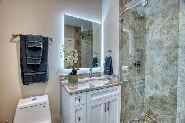 a bathroom with a granite countertop shower a sink and mirror