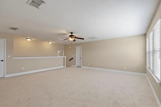 an empty room with windows and chandelier fan