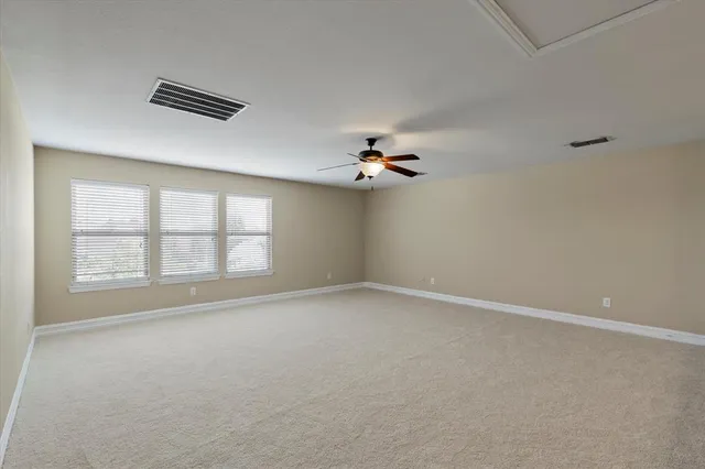 an empty room with windows and chandelier fan