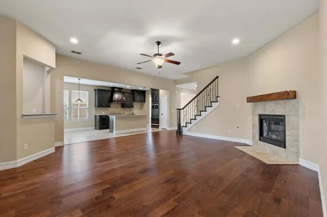 a view of an empty room with wooden floor and a kitchen