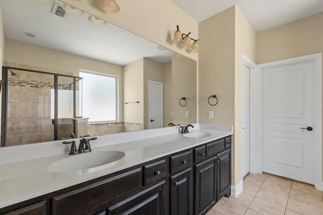 a spacious bathroom with a double vanity sink a mirror and a shower