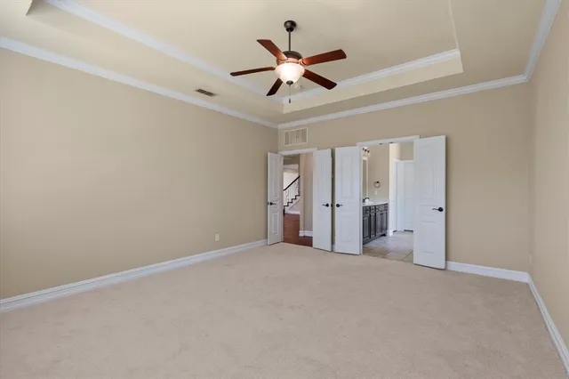 an empty room with a chandelier fan and windows
