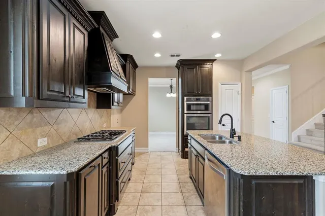 a kitchen with stainless steel appliances granite countertop a sink a stove and a refrigerator