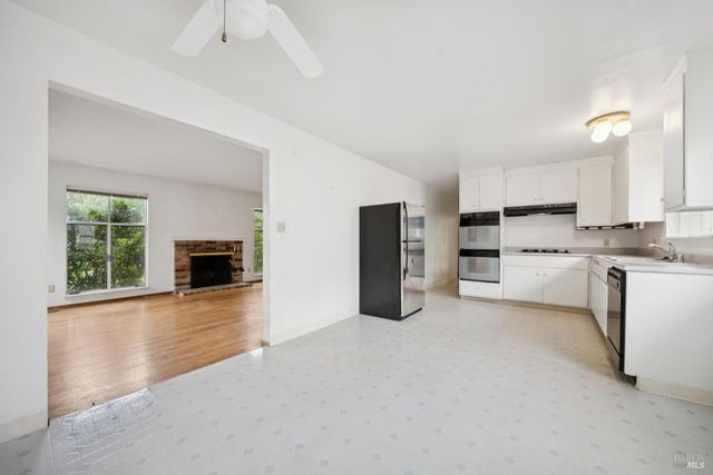 a large white kitchen with stainless steel appliances kitchen island granite countertop a large window and a sink