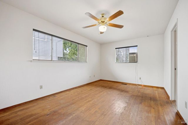 a view of a big room with wooden floor and windows