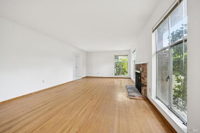 a view of a big room with wooden floor and windows