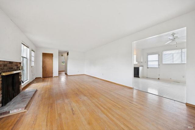 a view of empty room with wooden floor and fireplace