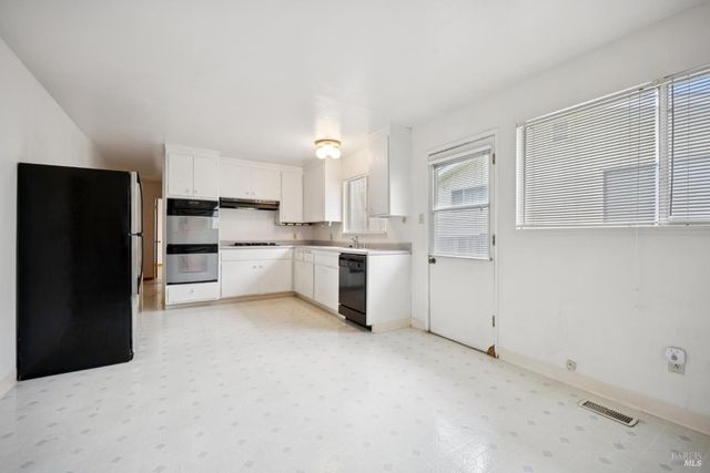a kitchen with white cabinets and refrigerator