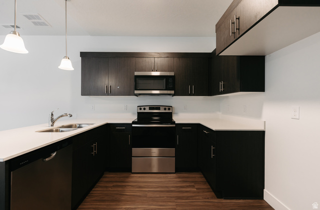 4655 South 720 West, Unit I303 Mapleton, UT 84664 - Photo 11 of 15 Kitchen featuring stainless steel appliances, a peninsula, dark wood-style flooring, hanging light fixtures, and light stone countertops