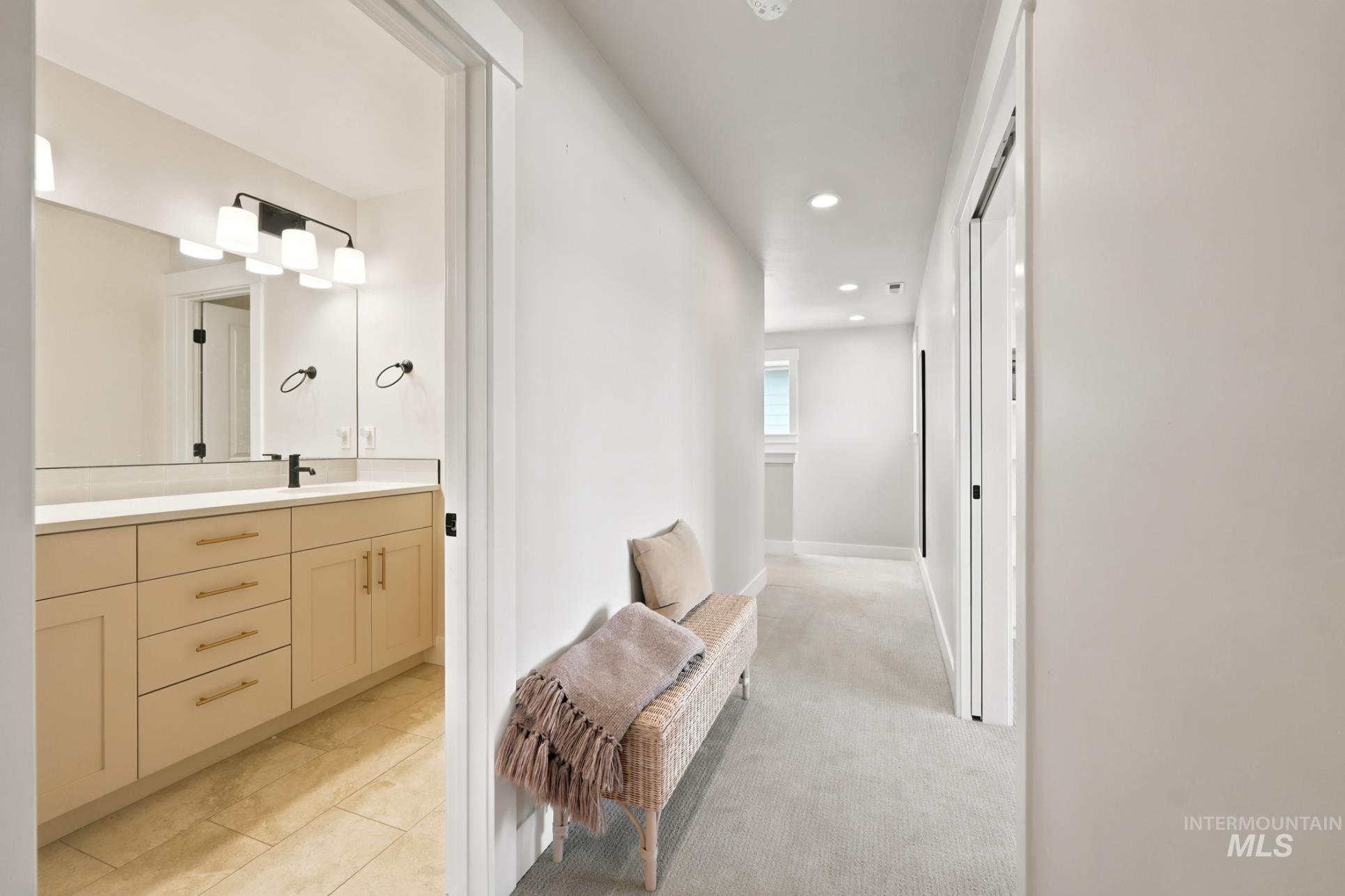 6933 South Zenith Avenue Meridian, ID 83642 - Photo 16 of 34 Hallway access to a bathroom featuring a light-toned vanity with gold-finish hardware, a large vanity mirror, and a matte black faucet