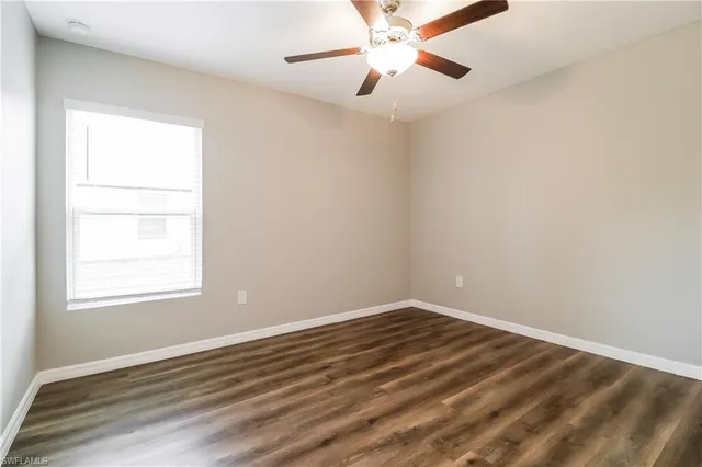 an empty room with a window and a fan