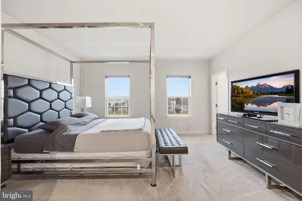 a bedroom with a large bed and a flat tv screen on dresser