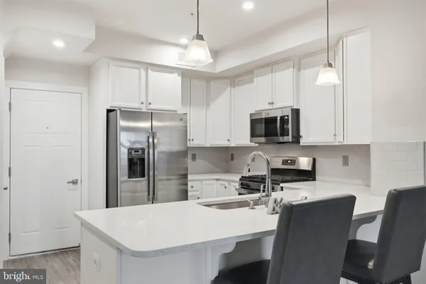 a kitchen with stainless steel appliances granite countertop a refrigerator a stove a microwave oven a sink with island and chairs