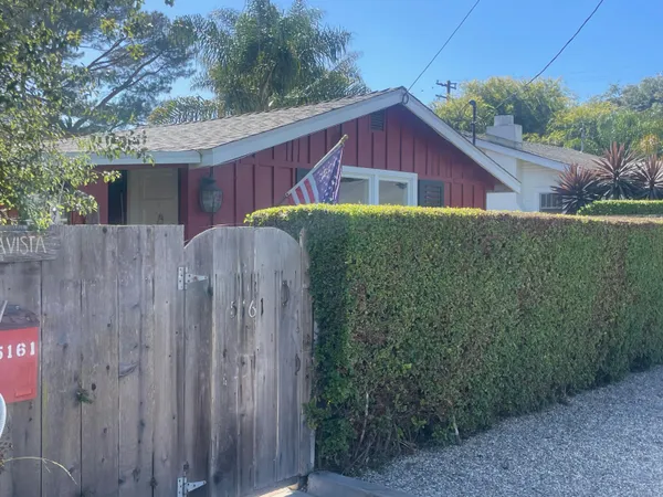 a view of a house with a small yard and wooden fence