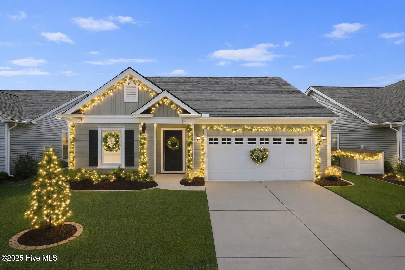 Virtually staged. A stunning twilight view of 9355 Eagle Ridge Drive illuminated with sophisticated Christmas lighting and garland, highlighting the home’s upscale coastal ambiance in the Eagle Run community