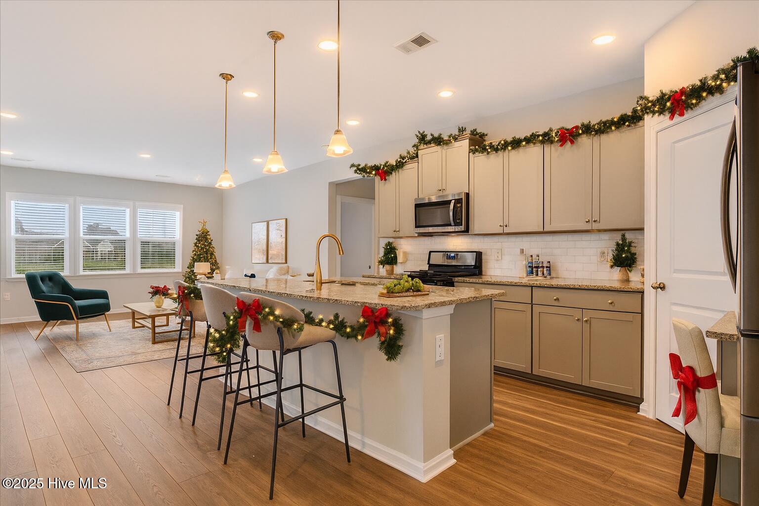 9355 Eagle Rdg Drive Calabash, NC 28467 - Photo 3 of 83 Virtually staged. Bright open-concept kitchen and living area adorned with elegant Christmas garland and subtle seasonal accents, highlighting the home’s luxury finishes and inviting coastal design.